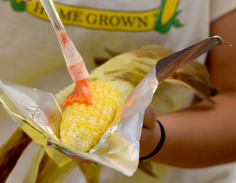 Jadyn Tulchinsky, of Brentwood, spreads butter on an ear of bi-colored roasted corn for $3 at the 2016 Brentwood Harvest Time Festival on Sunday, July 10, 2016 in Brentwood, Calif. (Susan Tripp Pollard/Bay Area News Group)
